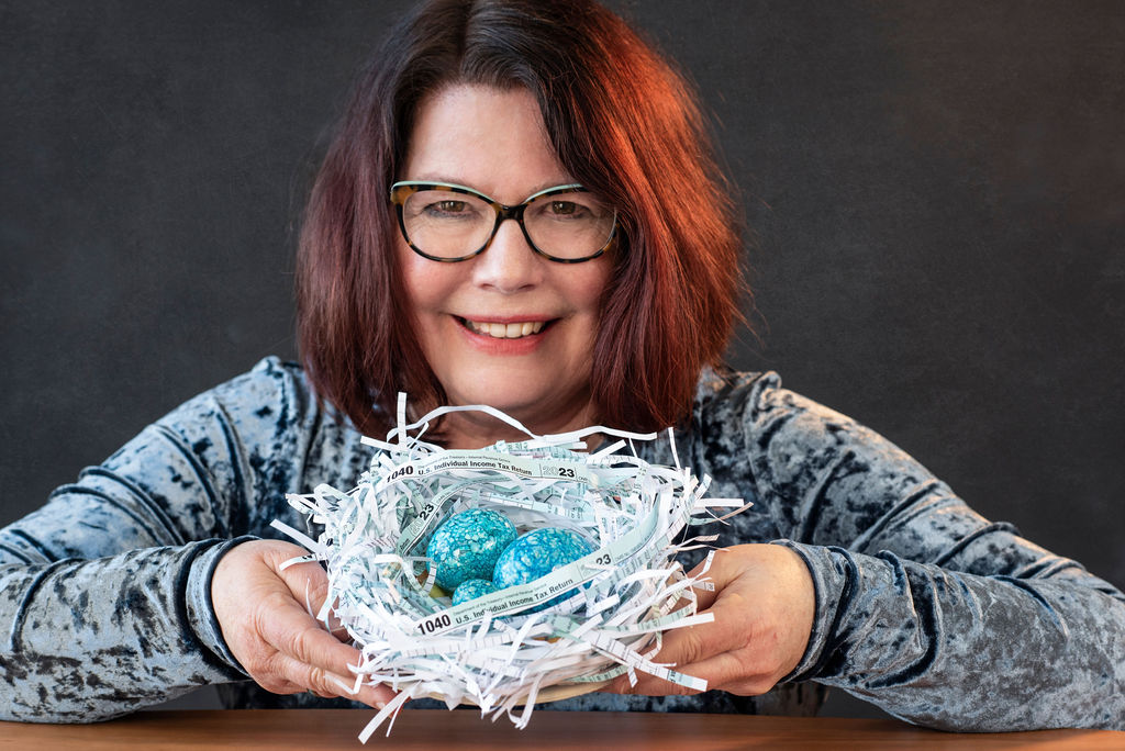 Woman with glasses holding a nest made of shredded tax forms.